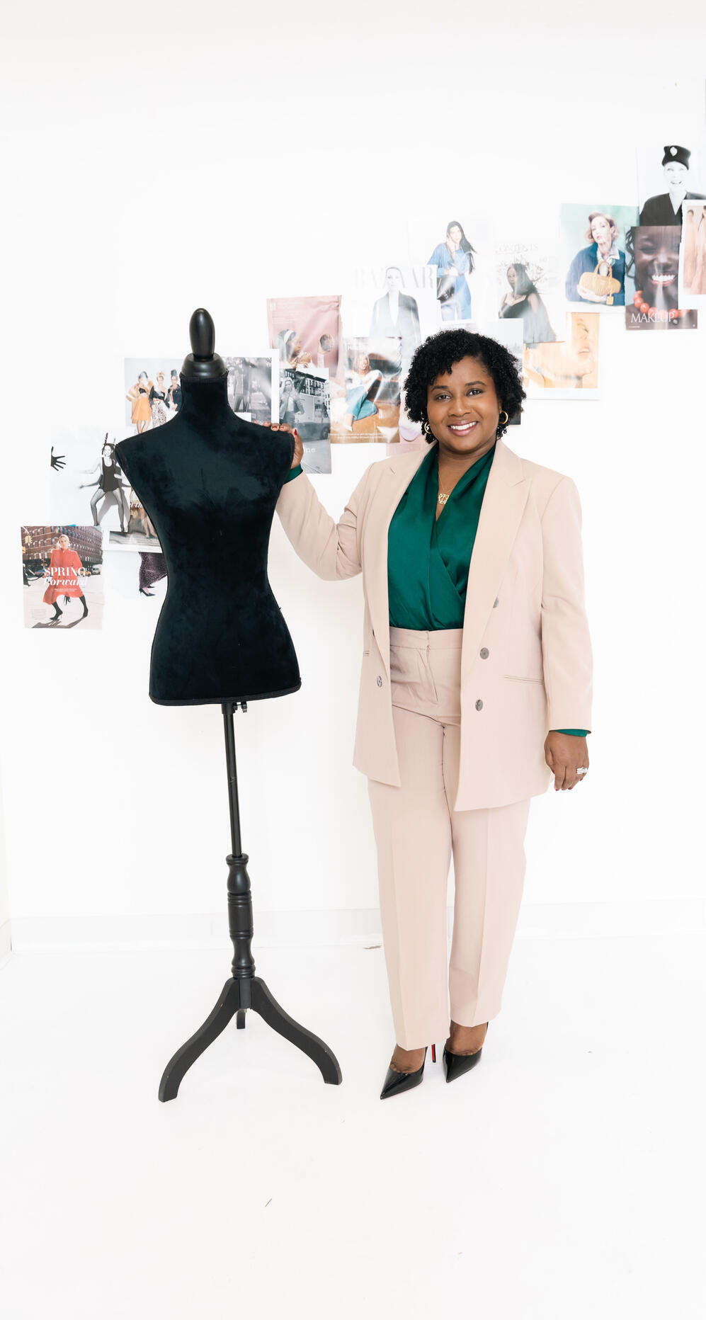bria-johnson-editorial-studio-cream-suit.jpg Bria Johnson standing beside a dress form in a cream suit, in an editorial studio setting.